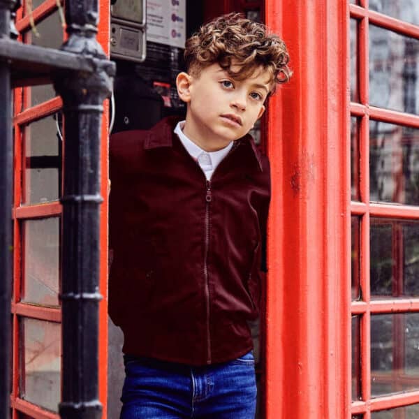 boy in telephone box wearing britannical burgundy jacket