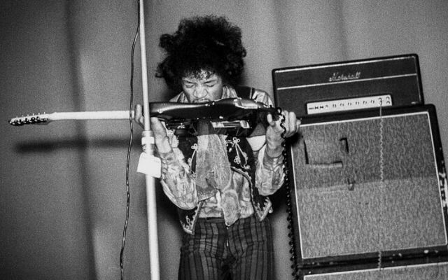 jimi hendrix playing his guitar with his teeth backed by a double marshall stack jimi hendrix playing his guitar with his teeth backed by a double marshall stack